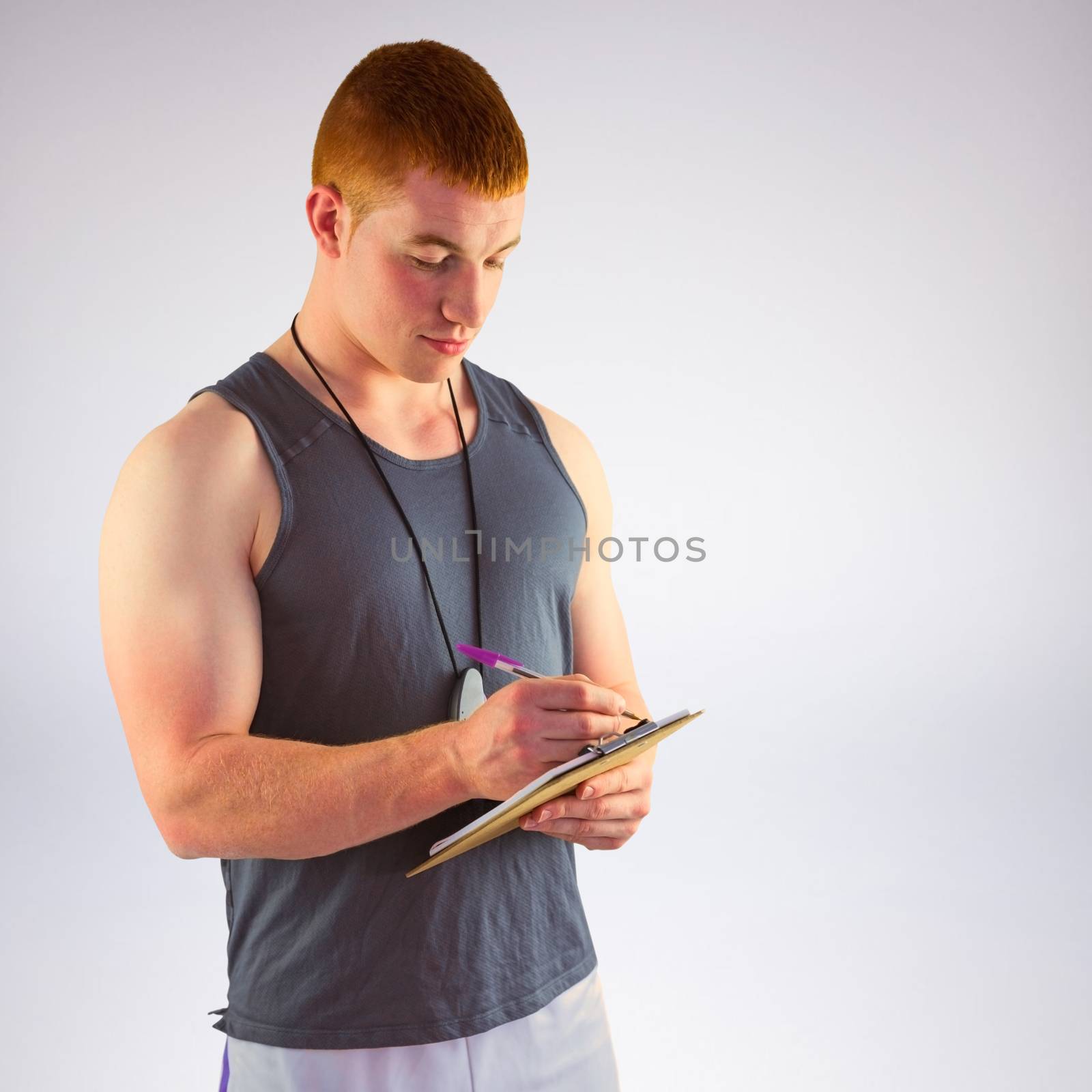 Composite image of fit personal trainer writing on clipboard by Wavebreakmedia