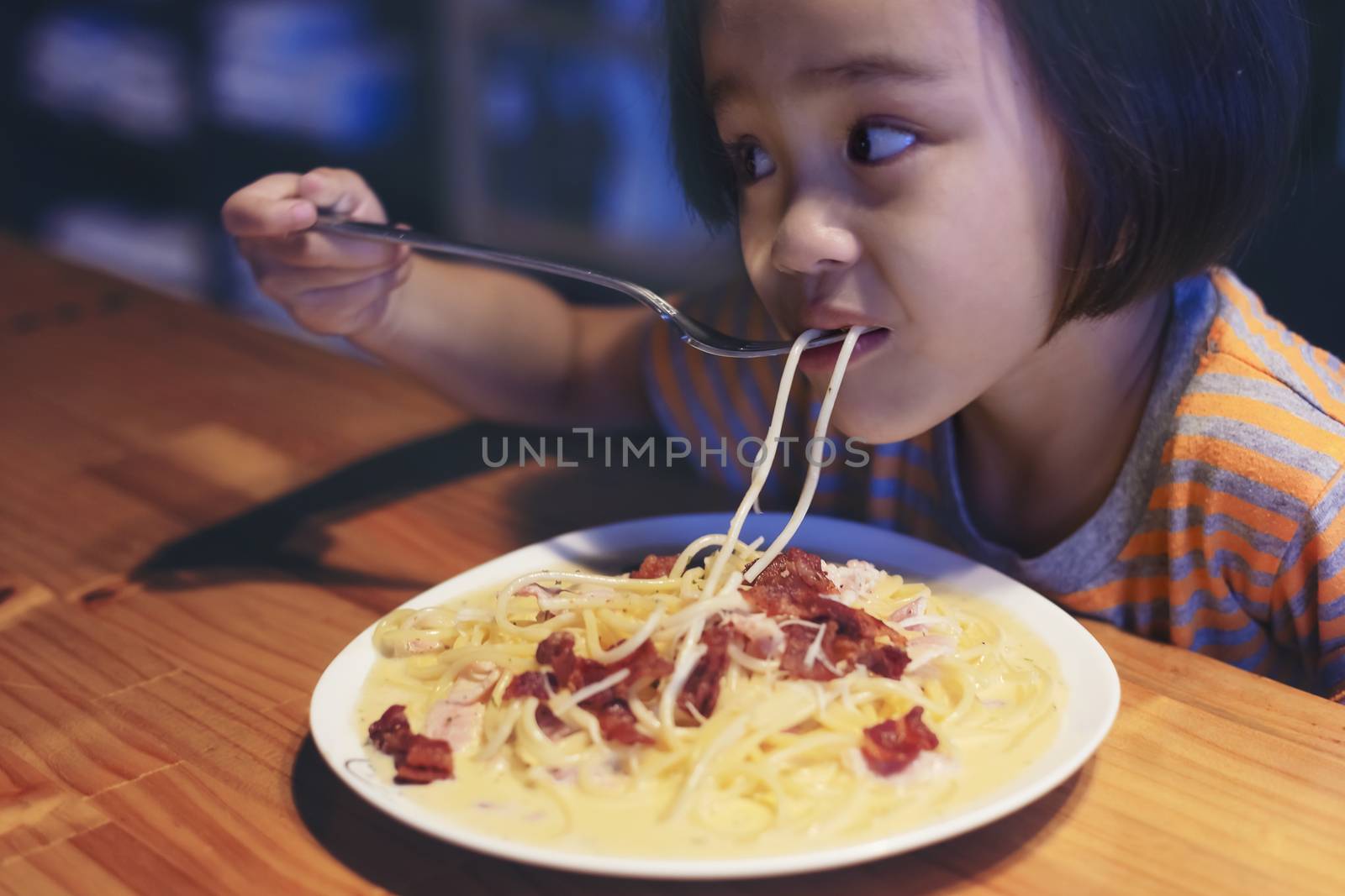 Asian little girl is eating spaghetti bolognese in the restauran by numberone9018