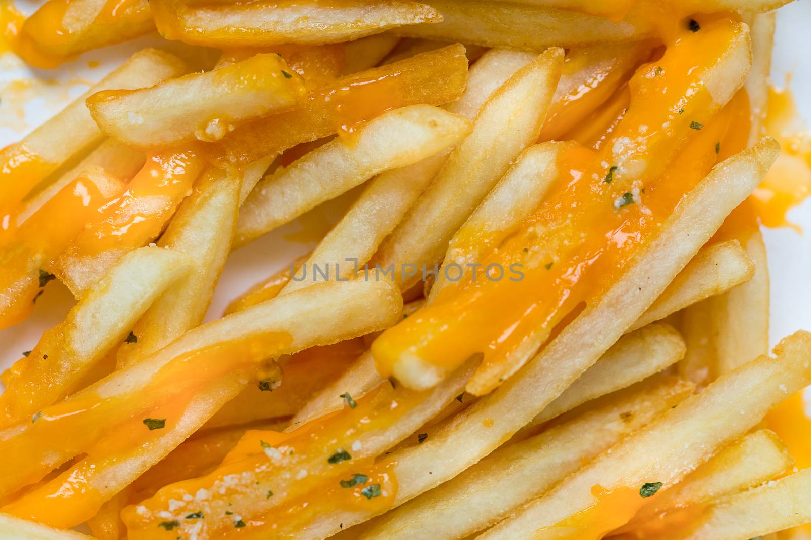 French fries with melted cheddar cheese background.