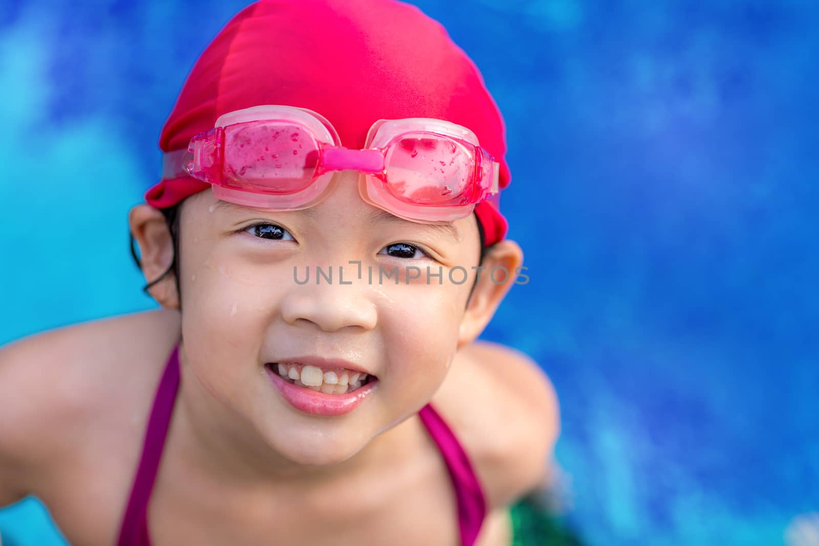 Happy smiling child in swimming pool outdoor.