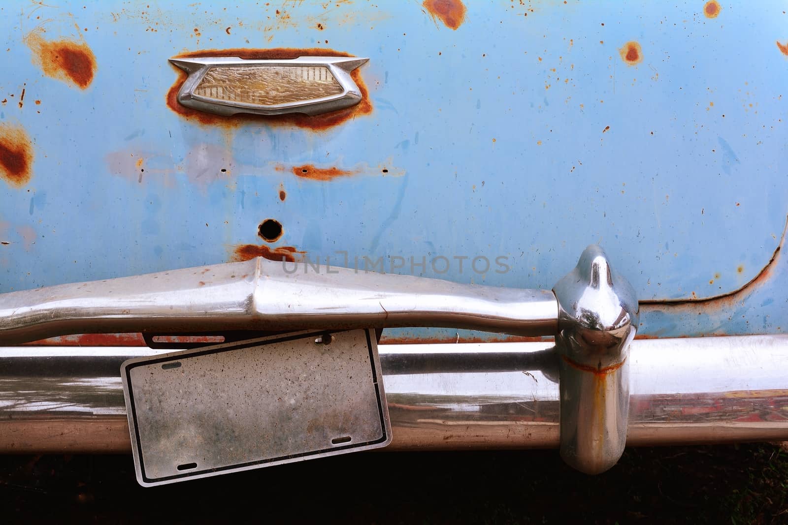 Rusty abandoned old car with number plate.