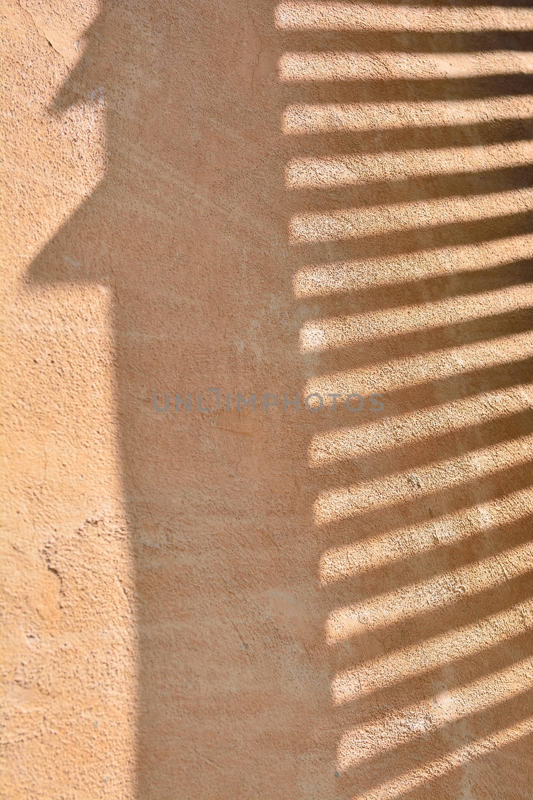 Morning sun beaming on the wall through window blinds.