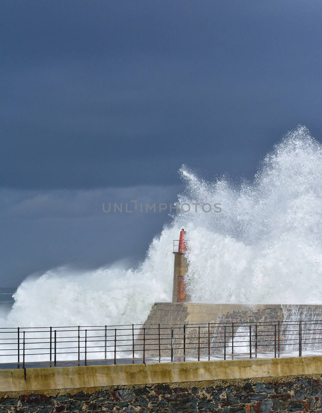 Stormy wave over old lighthouse and pier of Viavelez. by CreativePhotoSpain