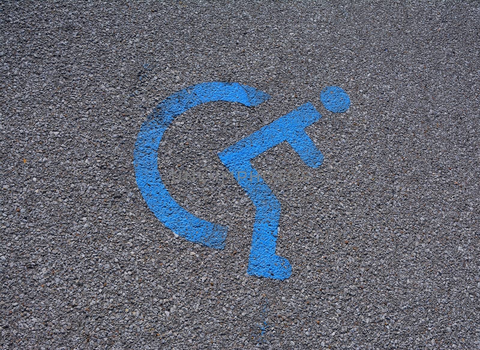 Disabled blue parking sign painted on dark asphalt.