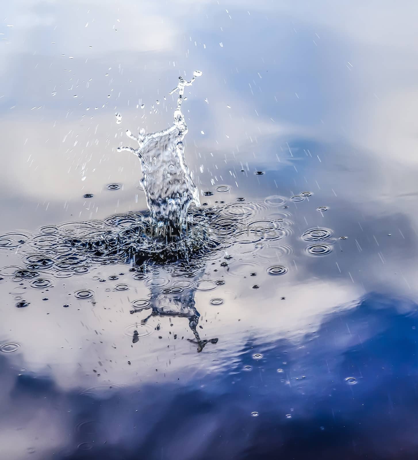 Beautiful water at a lake with splashing water and ripples on the surface with clouds and sky reflections