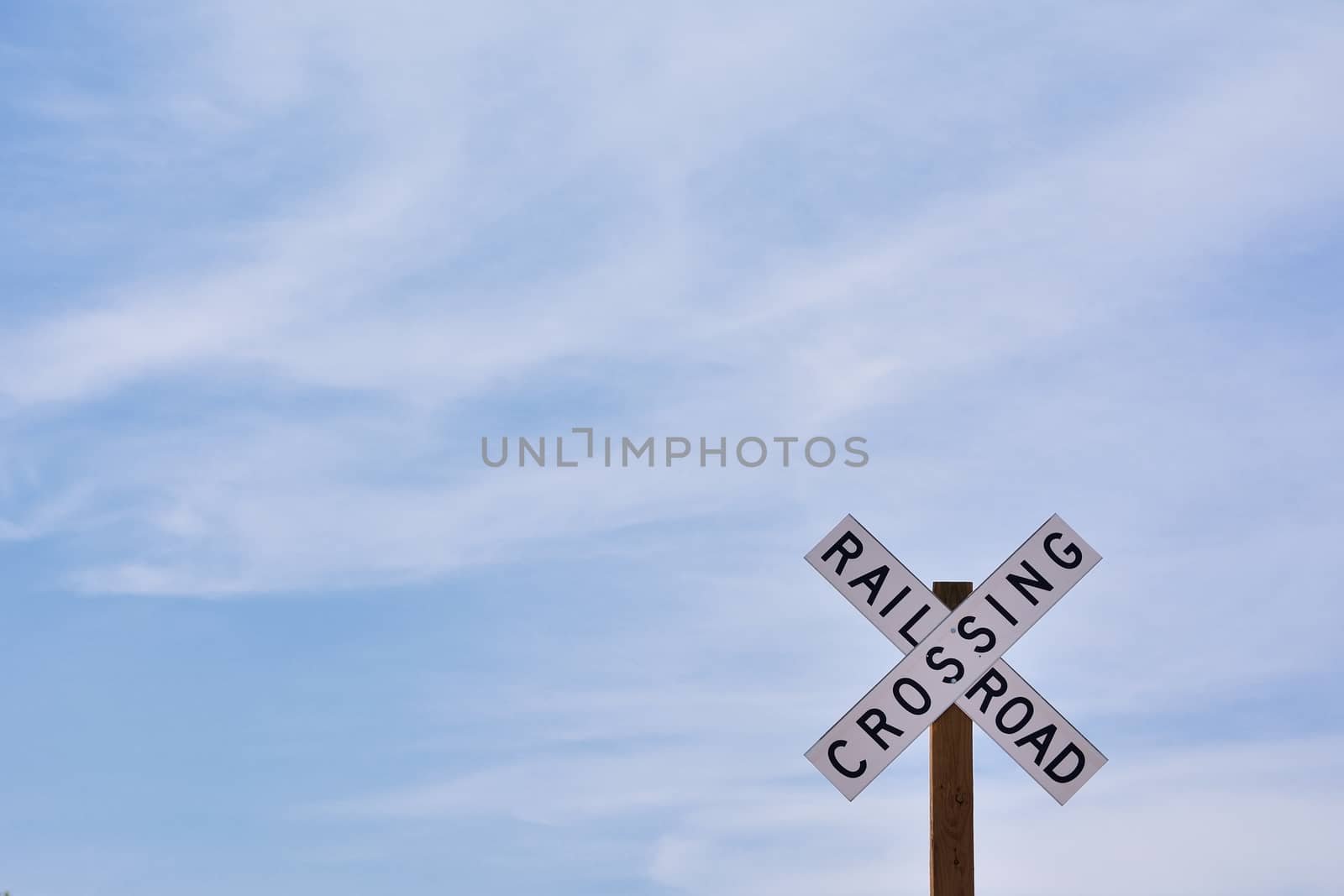 Railroad crossing sign against blue sky background, with space for your text.