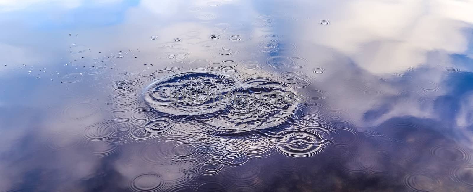 Beautiful water at a lake with splashing water and ripples on the surface with clouds and sky reflections