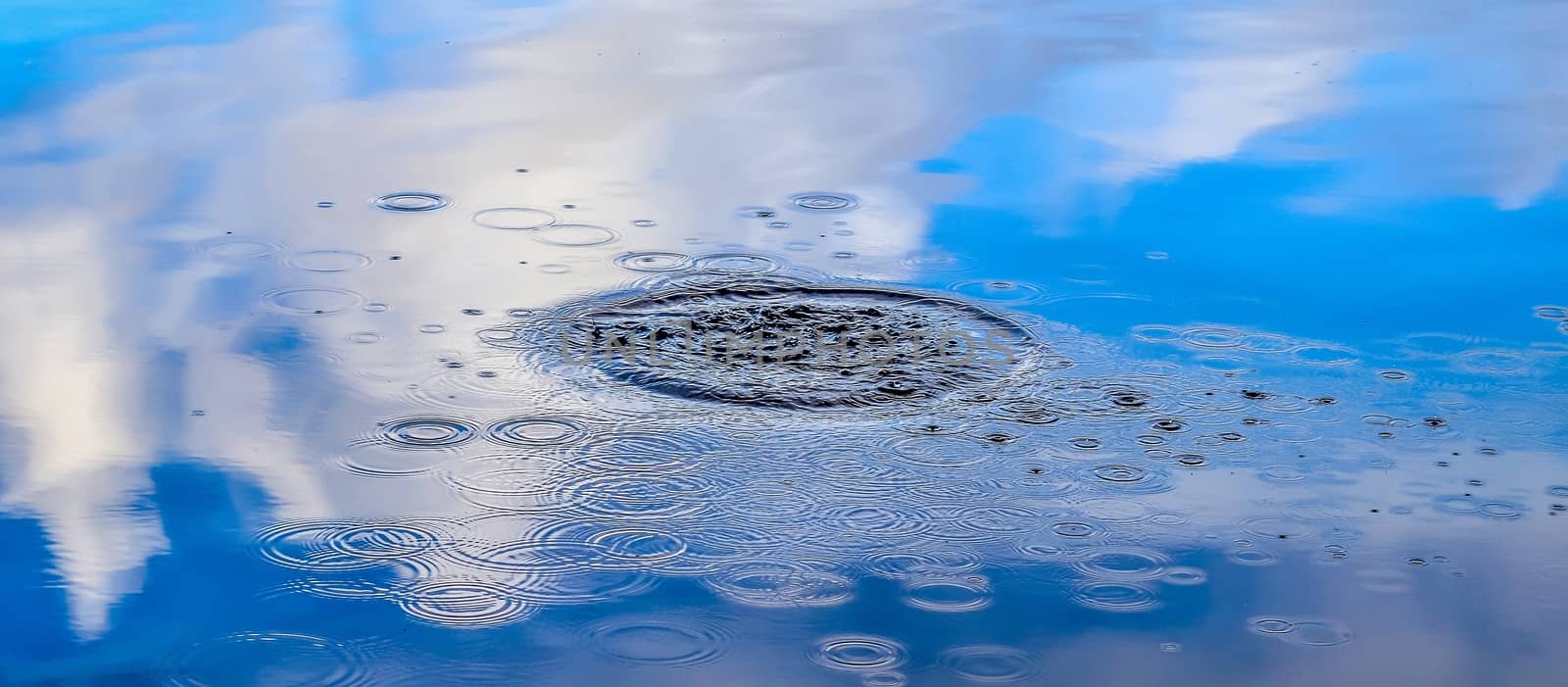 Beautiful water at a lake with splashing water and ripples on the surface with clouds and sky reflections