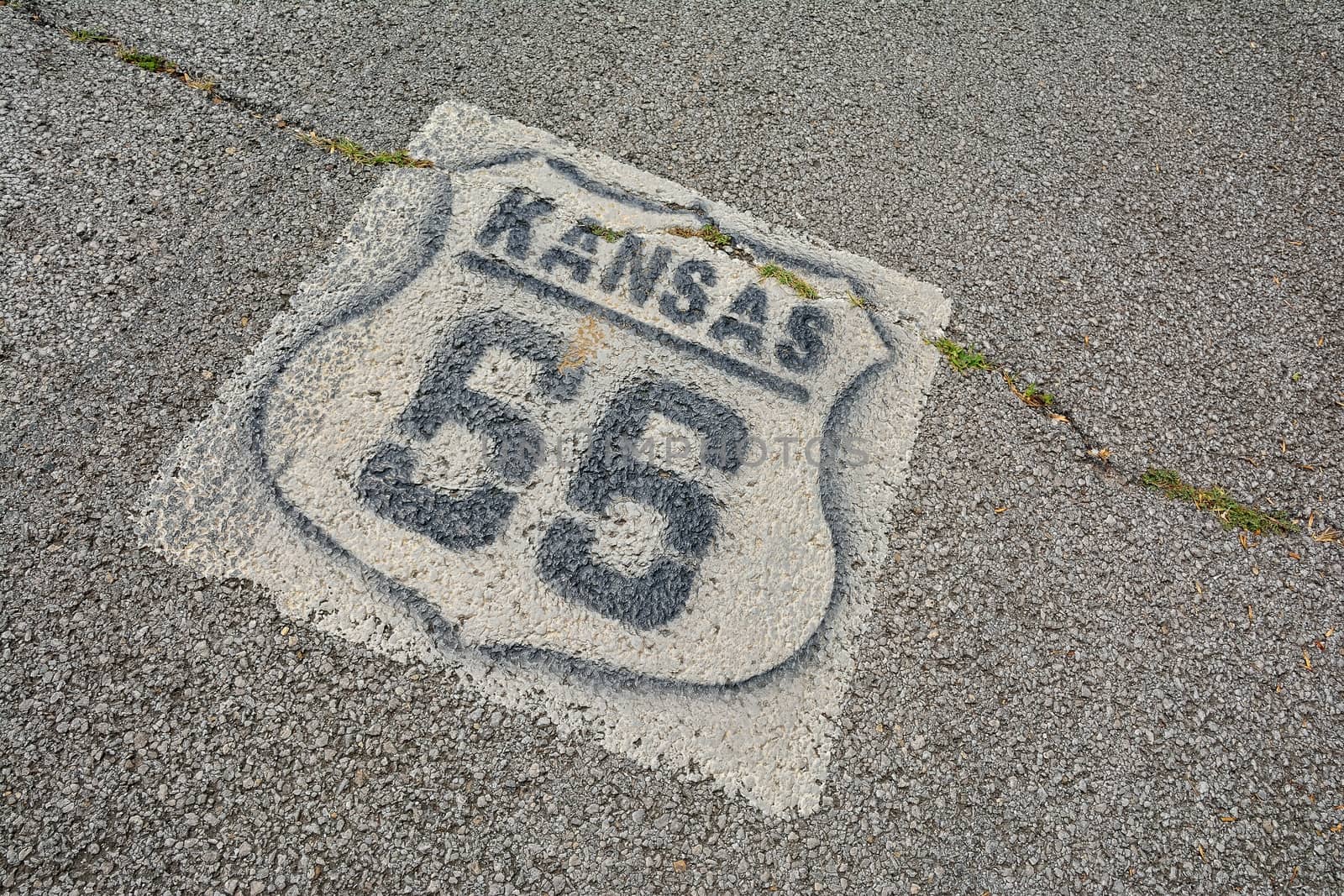 Historic Route 66 marker in Kansas on asphalt.