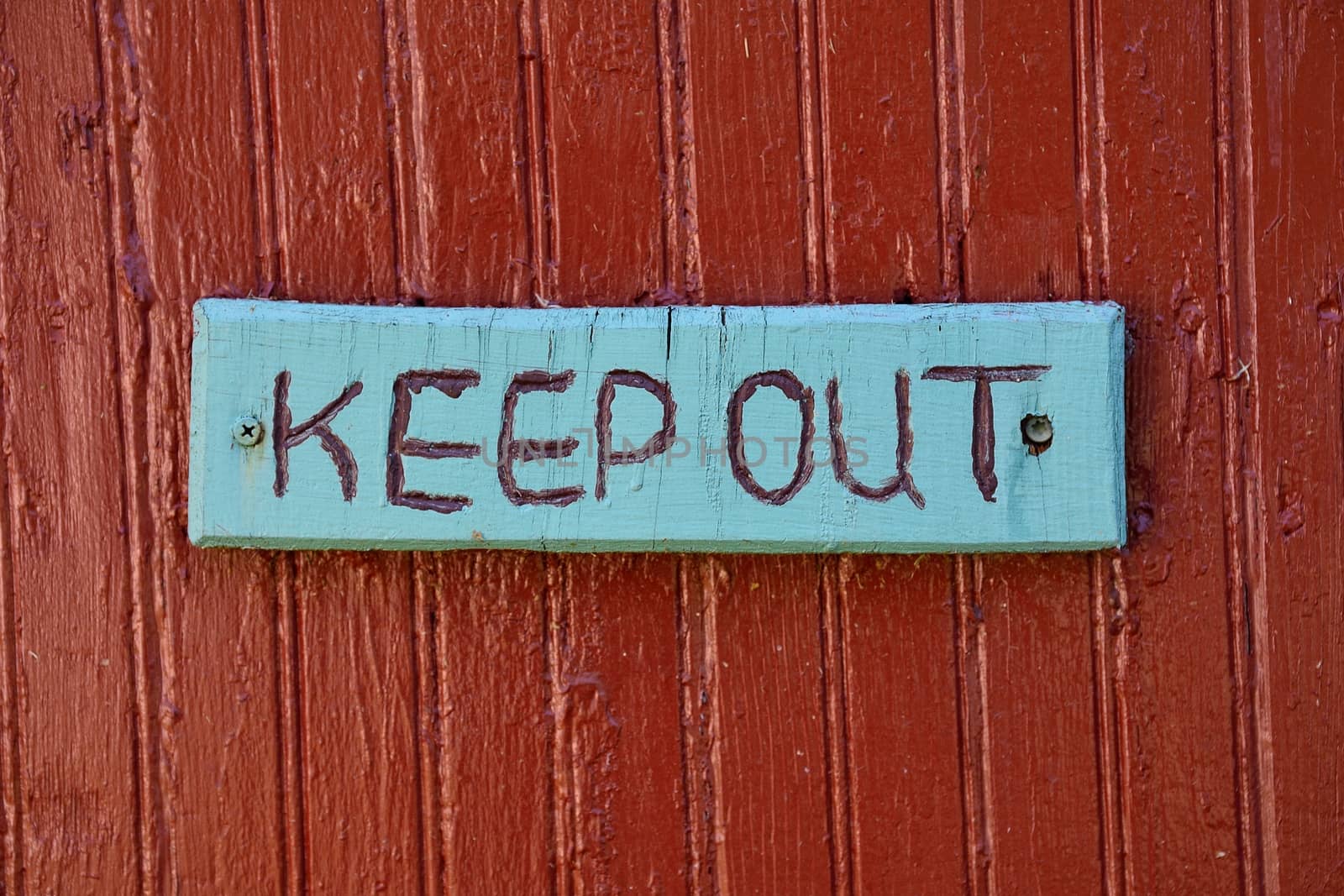Keep out sign over old rustic wooden textured surface.