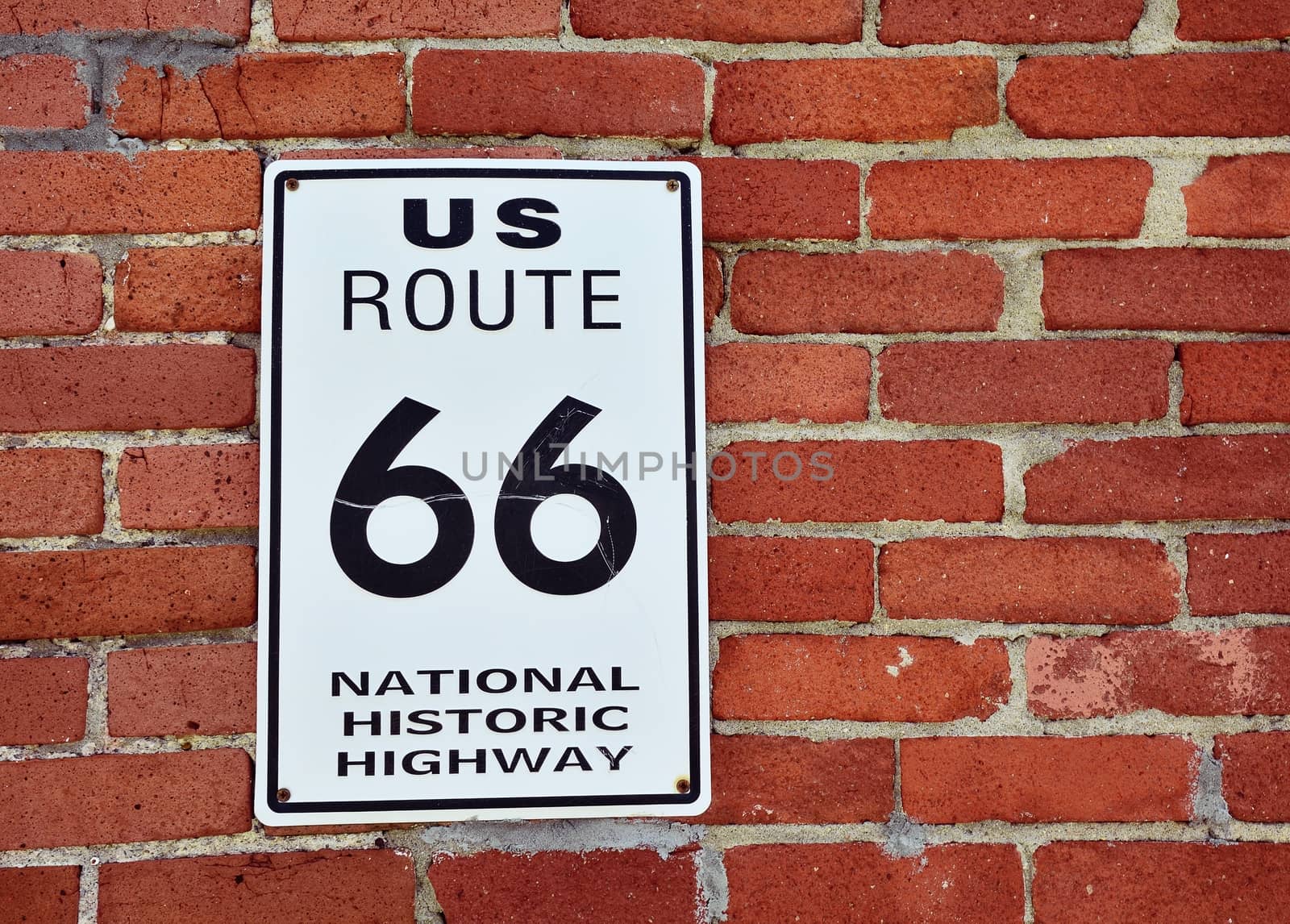 Historic US Route 66 road sign on a brick wall in Kansas.