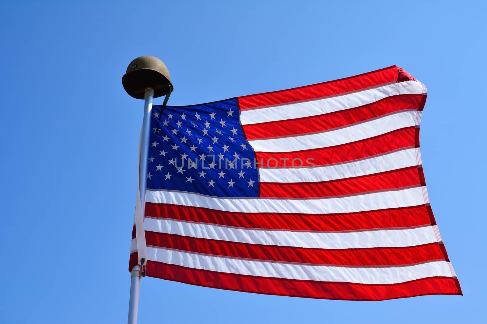 United States flag waving with a military helmet on the mast