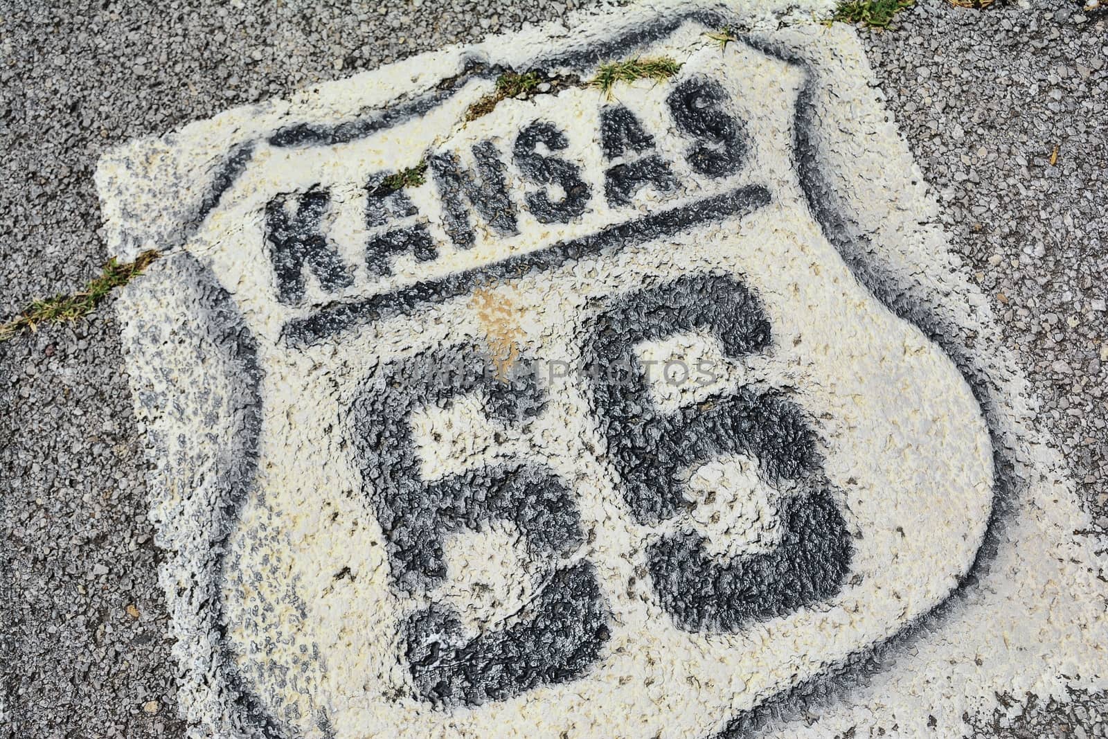 Historic Route 66 marker in Kansas on asphalt.