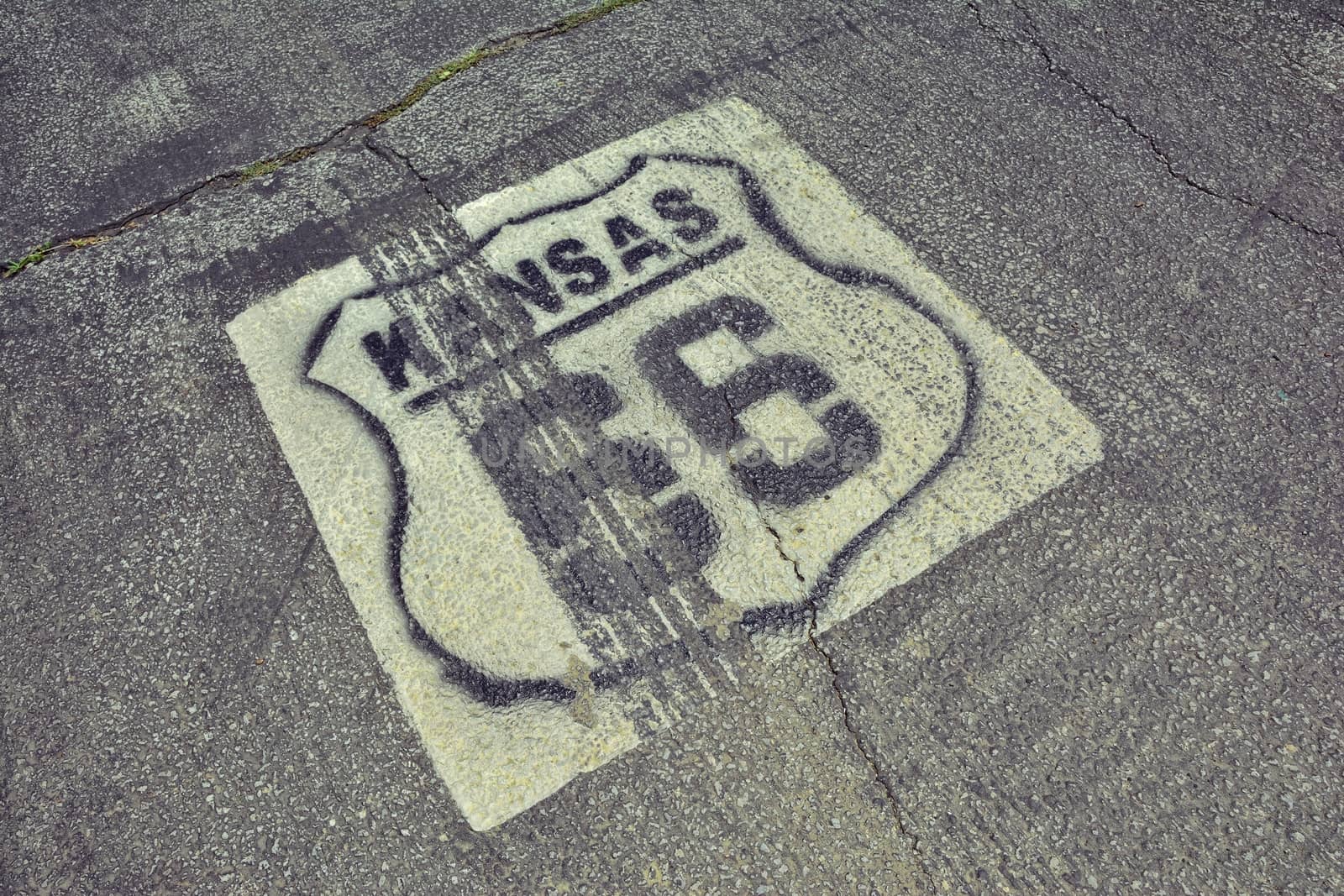 Historic Route 66 marker in Kansas on asphalt.