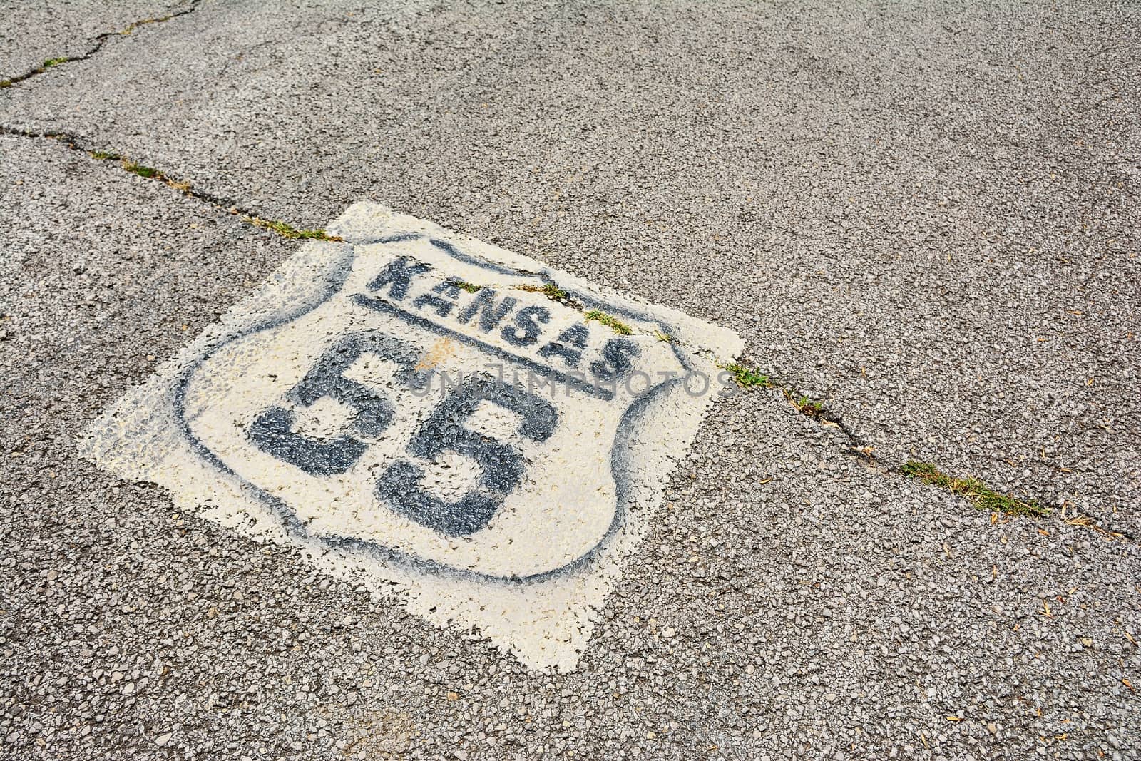 Historic Route 66 marker in Kansas on asphalt.