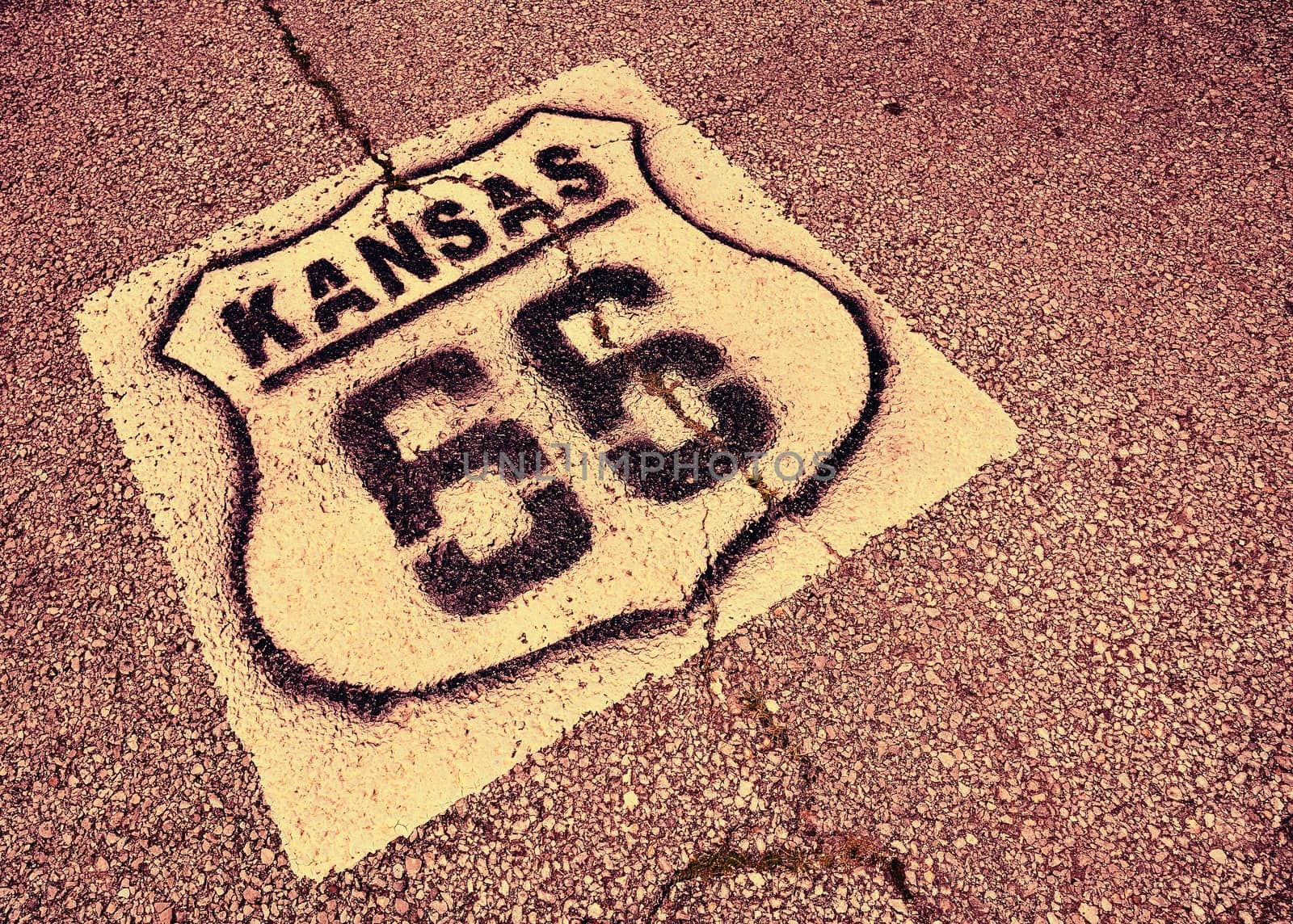 Historic Route 66 marker in Kansas on asphalt.