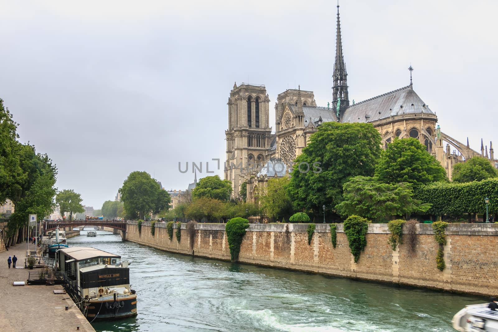 Paris, France - May 8, 2017 - Side view of Notre Dame Cathedral on the Seine with barges on a spring day