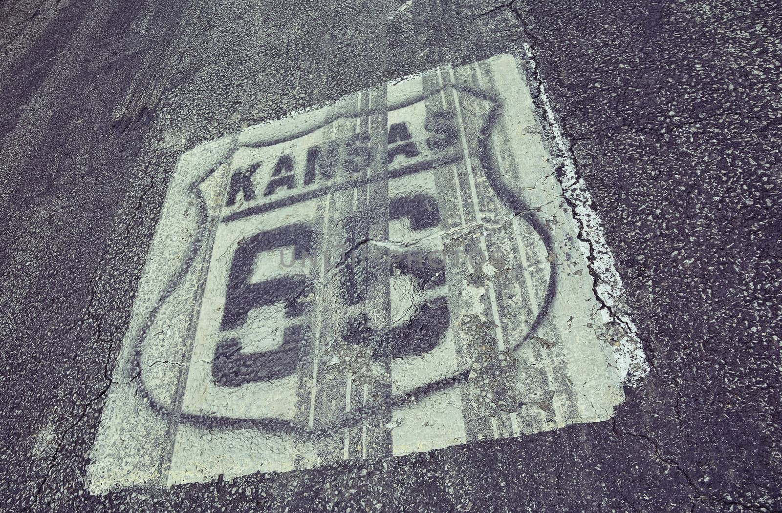Historic Route 66 marker in Kansas on asphalt.