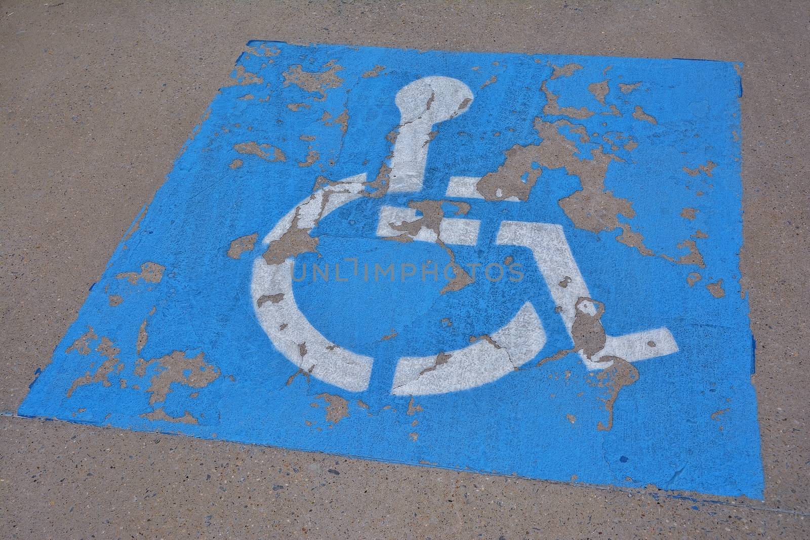 Disabled blue parking sign painted on dark asphalt.