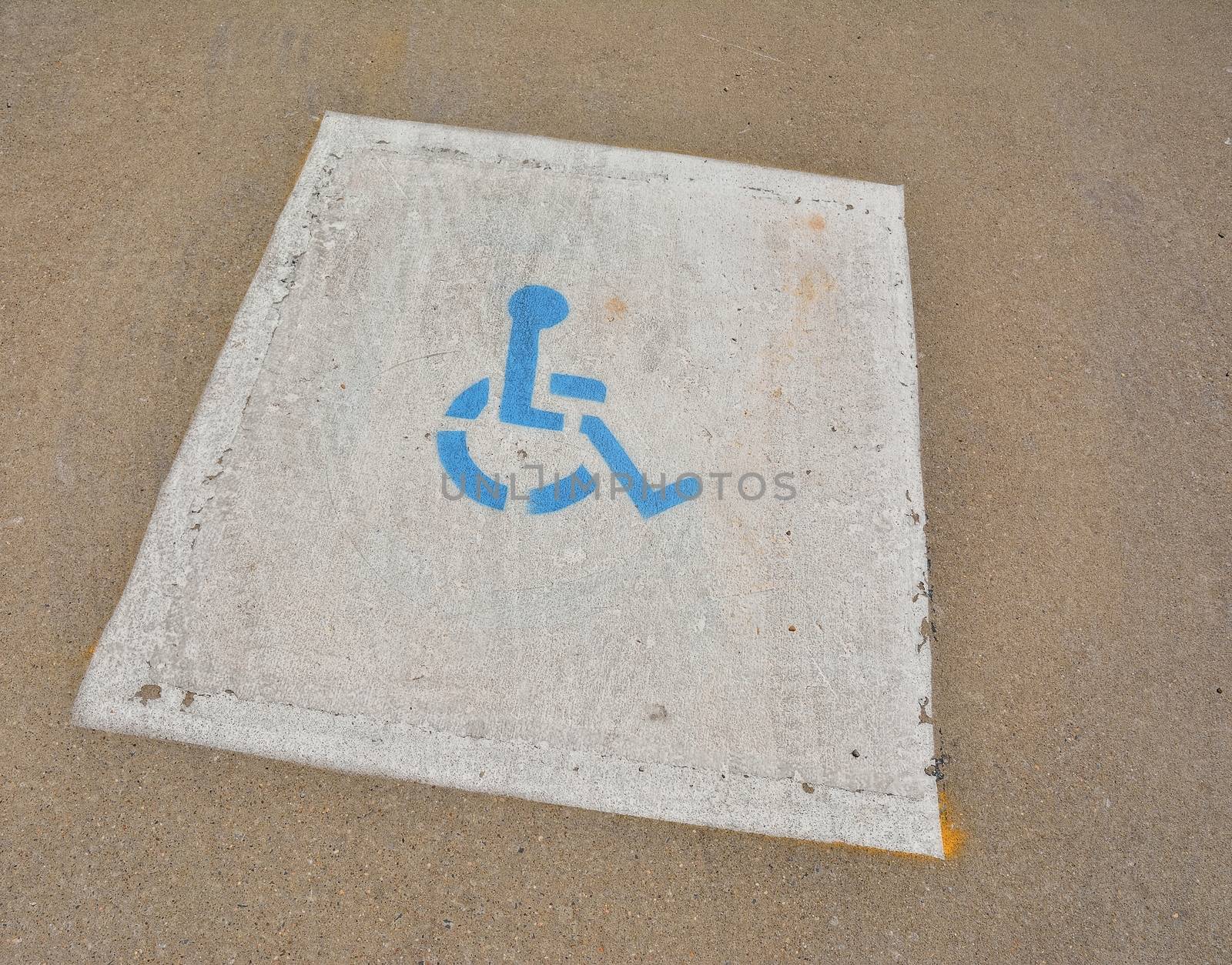 Disabled blue parking sign painted on asphalt.