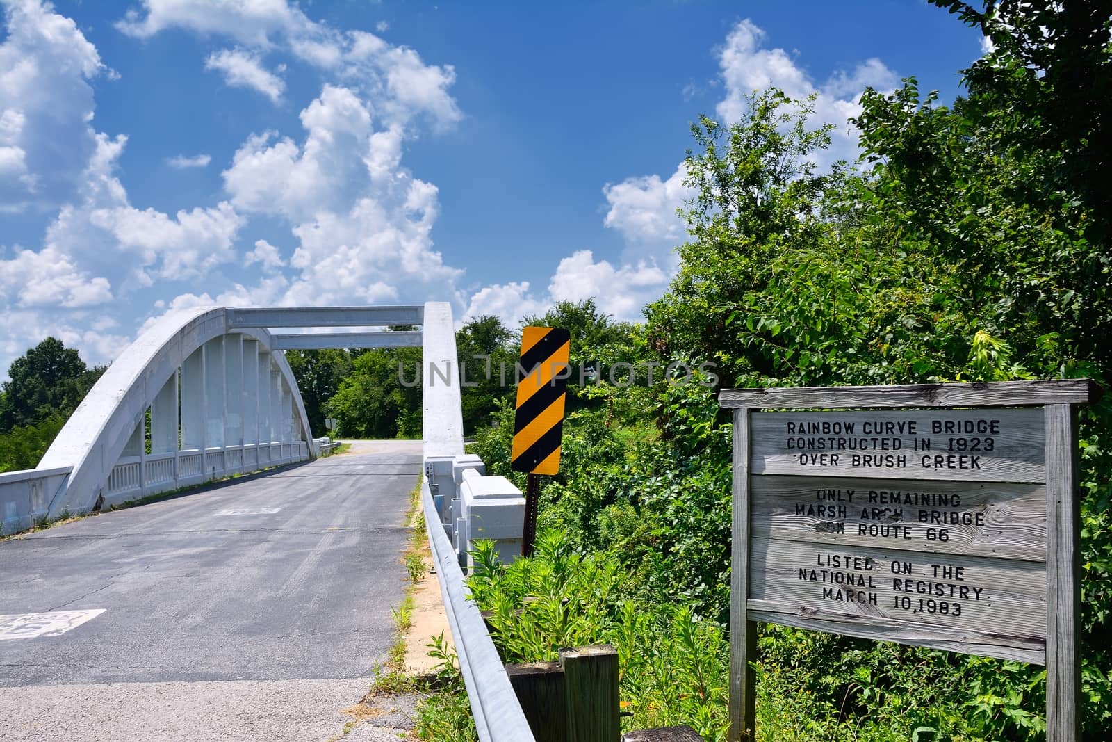 Close up of this Rainbow Curve Bridge Constructed in 1923 that is the only remaining Marsh Arch Bridge on Route 66. Route 66 signs are painted on the pavement.