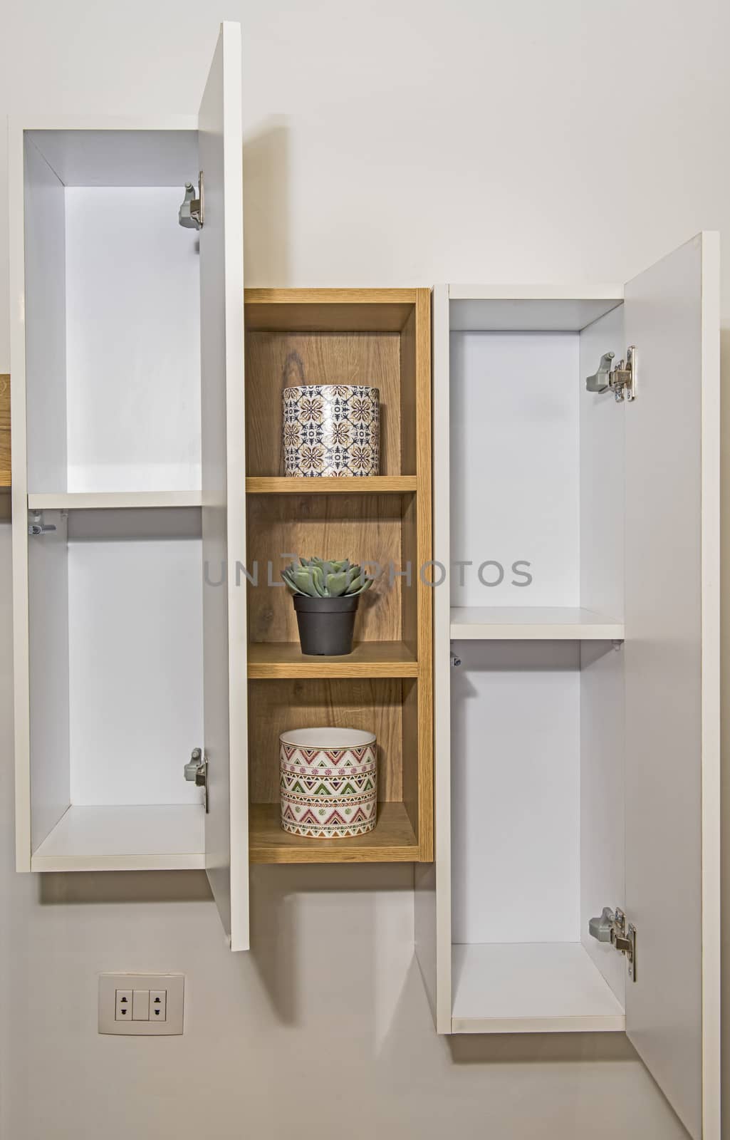 Interior design decor showing modern wooden shelf unit with cupboards in luxury apartment showroom