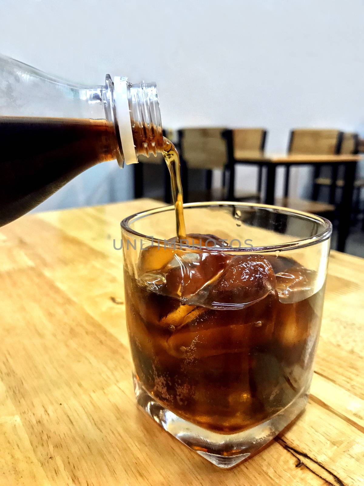 Cola in glass ice, Pouring cola from glass bottles drinks to a glass with ice cubes, cola in glass ice beverage Drinks on the restaurant table by cgdeaw