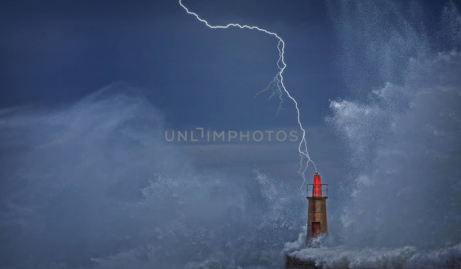 Lightning and wave over old lighthouse and pier of Viavelez in Asturias, Spain.