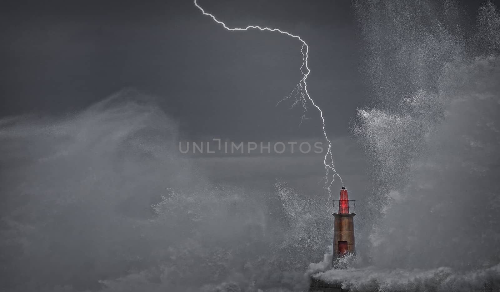 Lightning and wave over old lighthouse and pier of Viavelez in Asturias, Spain.