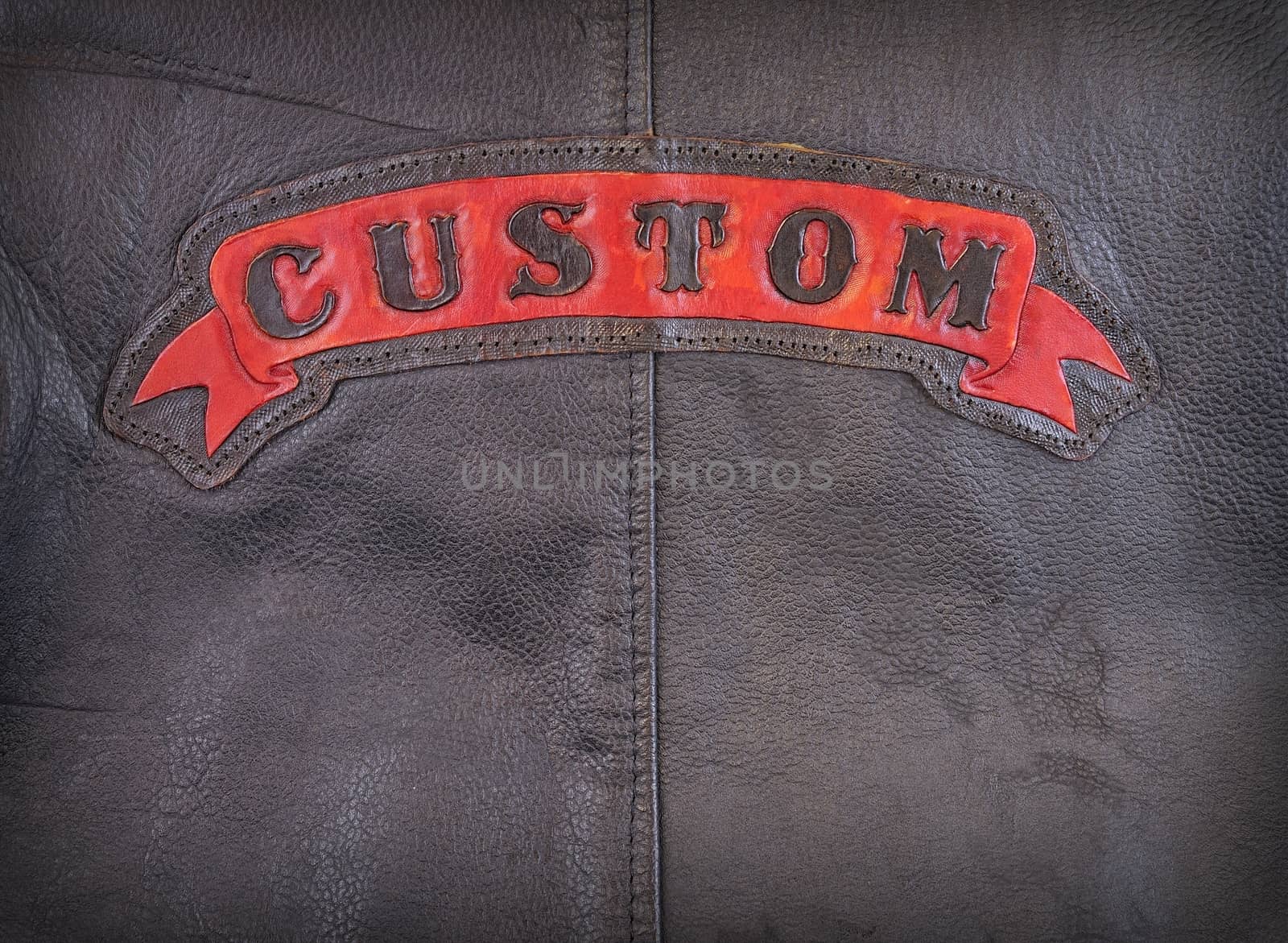 Red custom label on back of leather jacket in close-up.