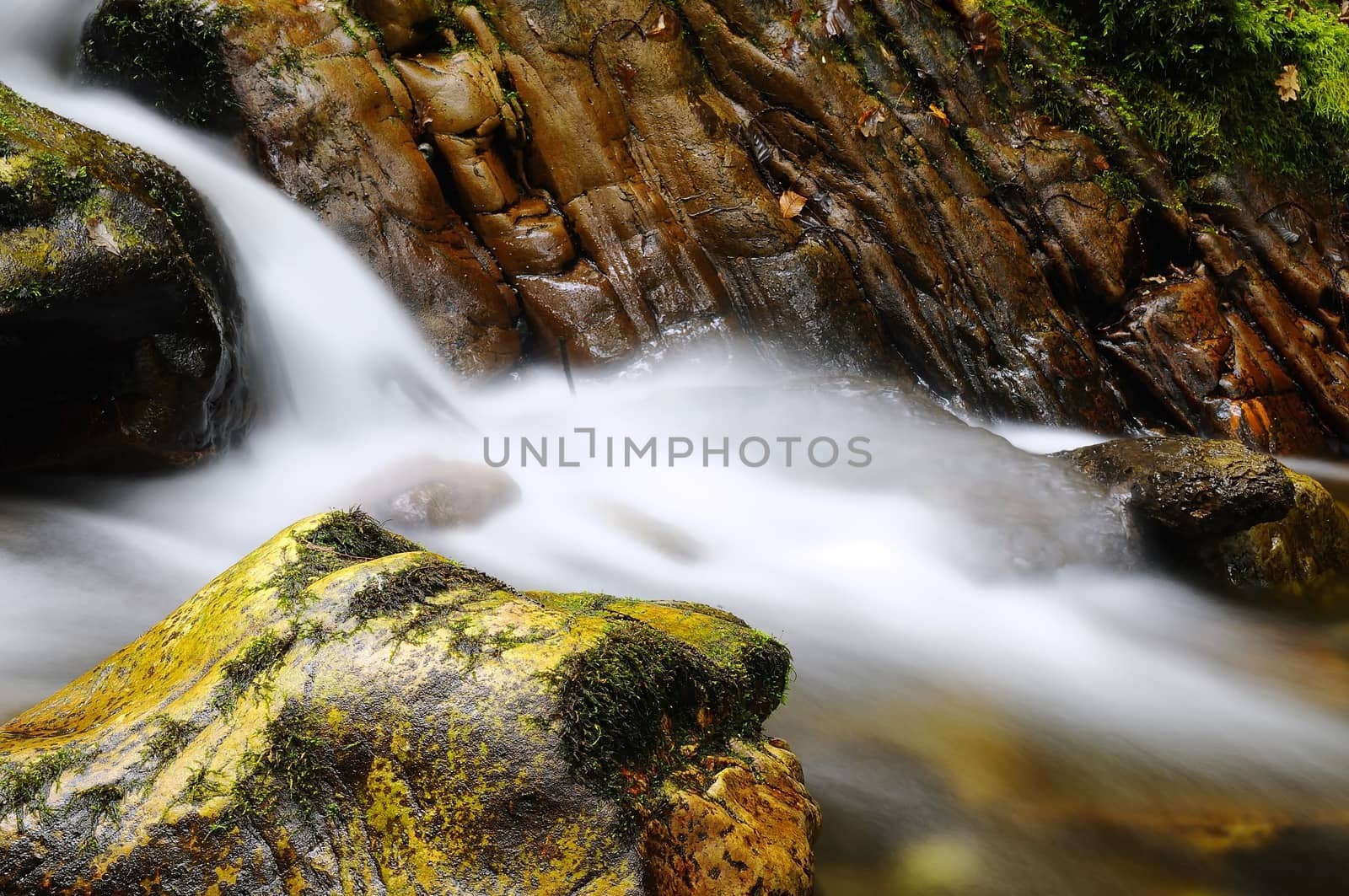 Long exposure shot of waterfall between stones covered with moss
