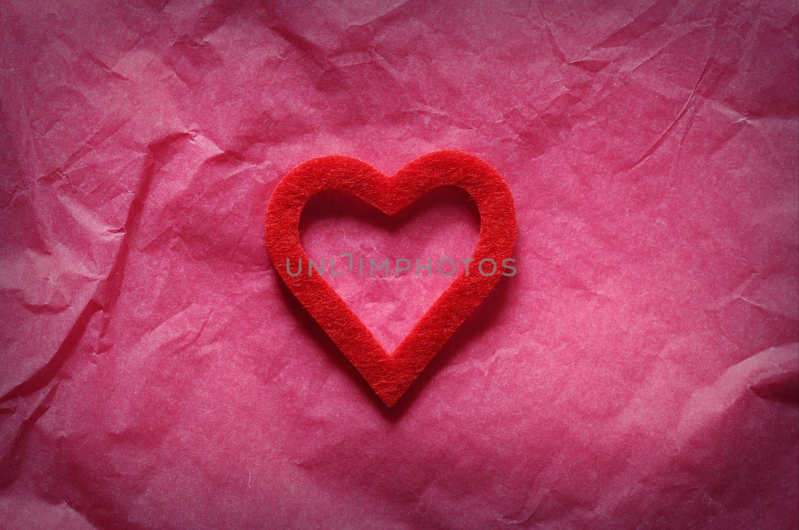 Red heart on pink paper.From above