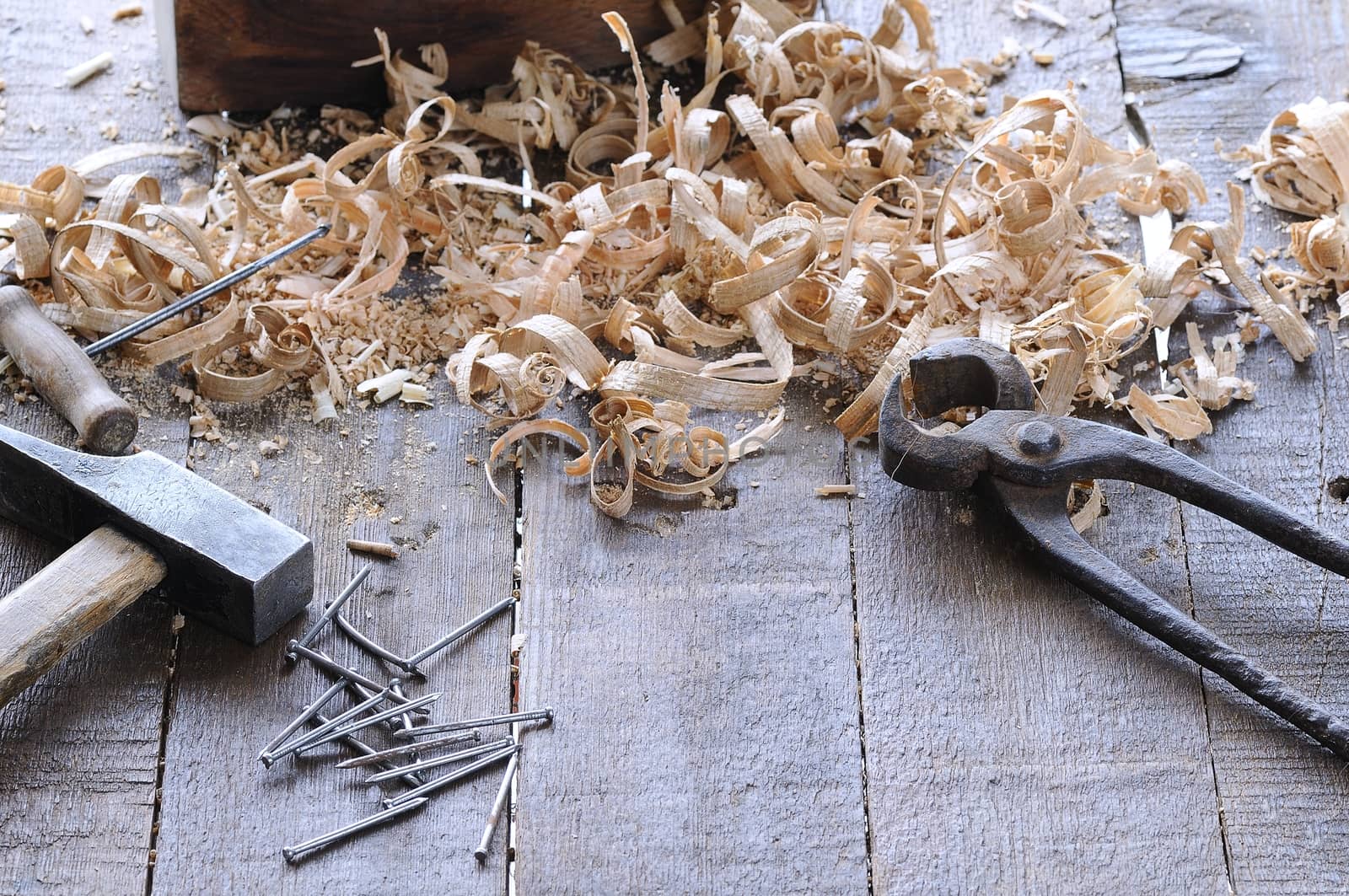 Spiral wooden chips with pincers, hammer, awl and nails on wooden floor