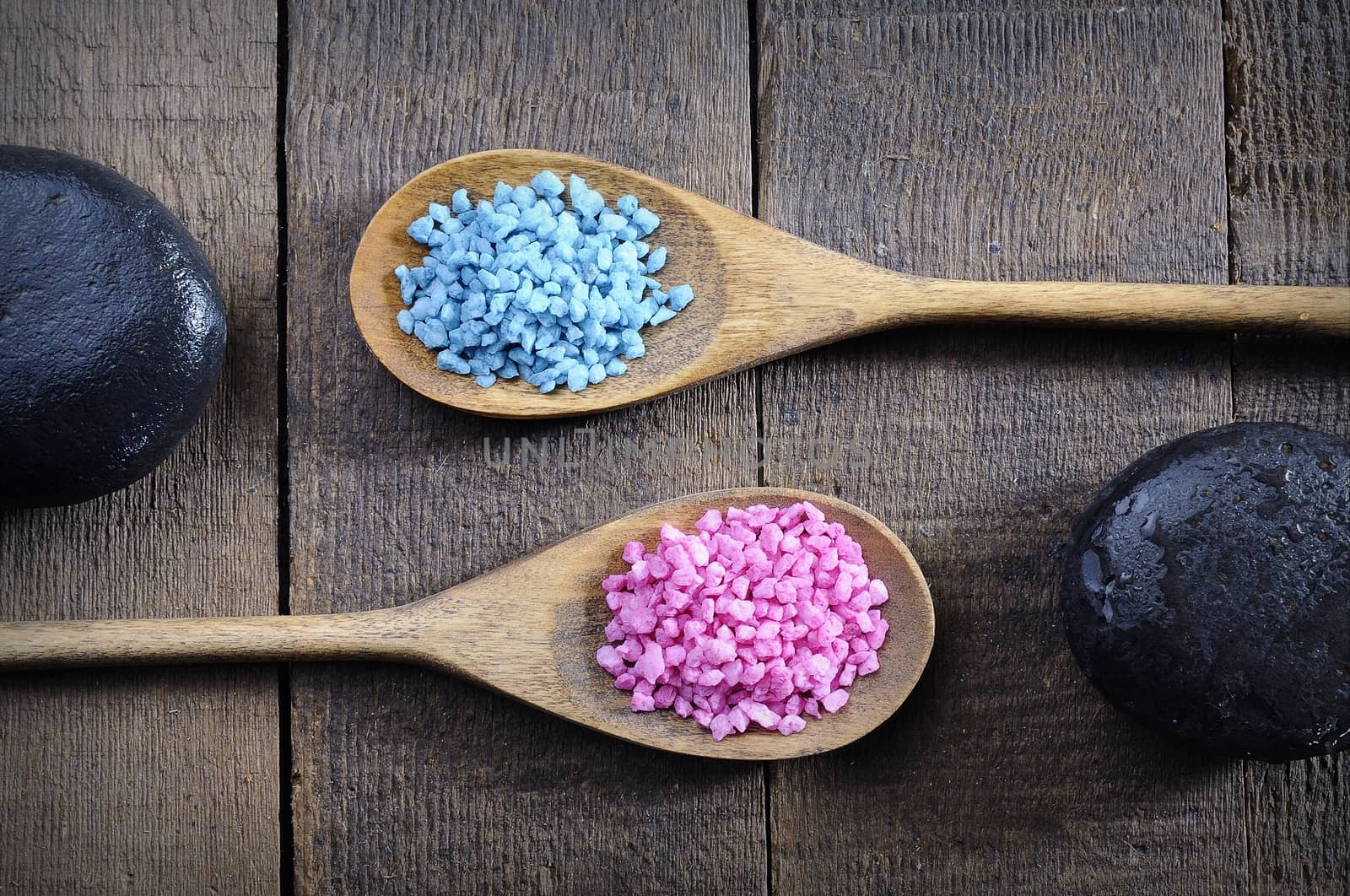 Blue and pink sea salt and spa stones on wooden background. From above.
