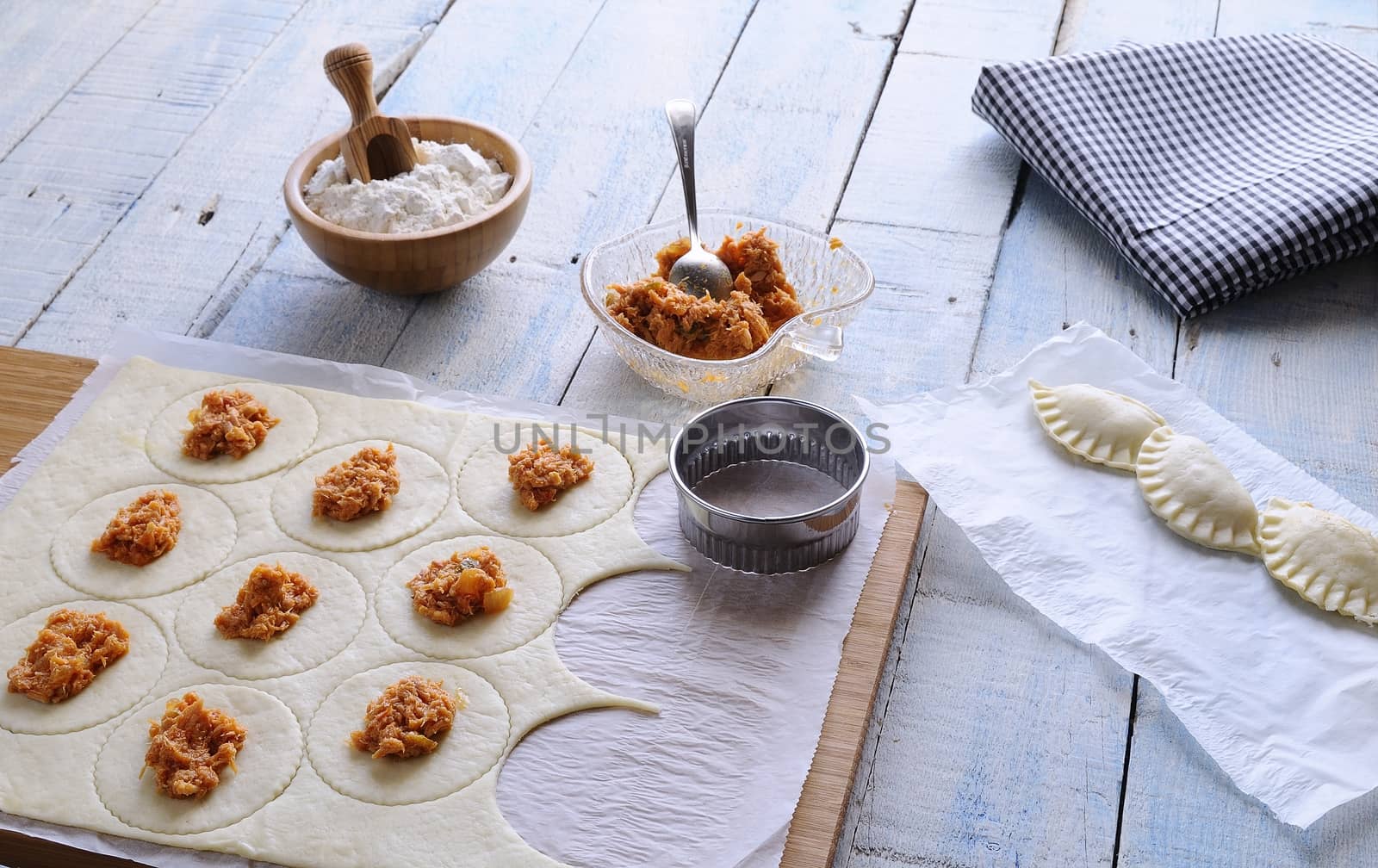 Raw dumplings and utensils on table