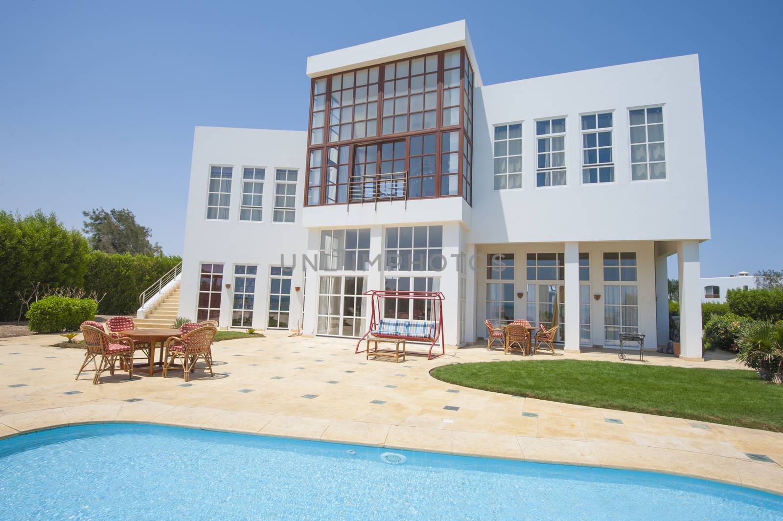 Luxury villa show home in tropical summer holiday resort with swimming pool and sun chairs