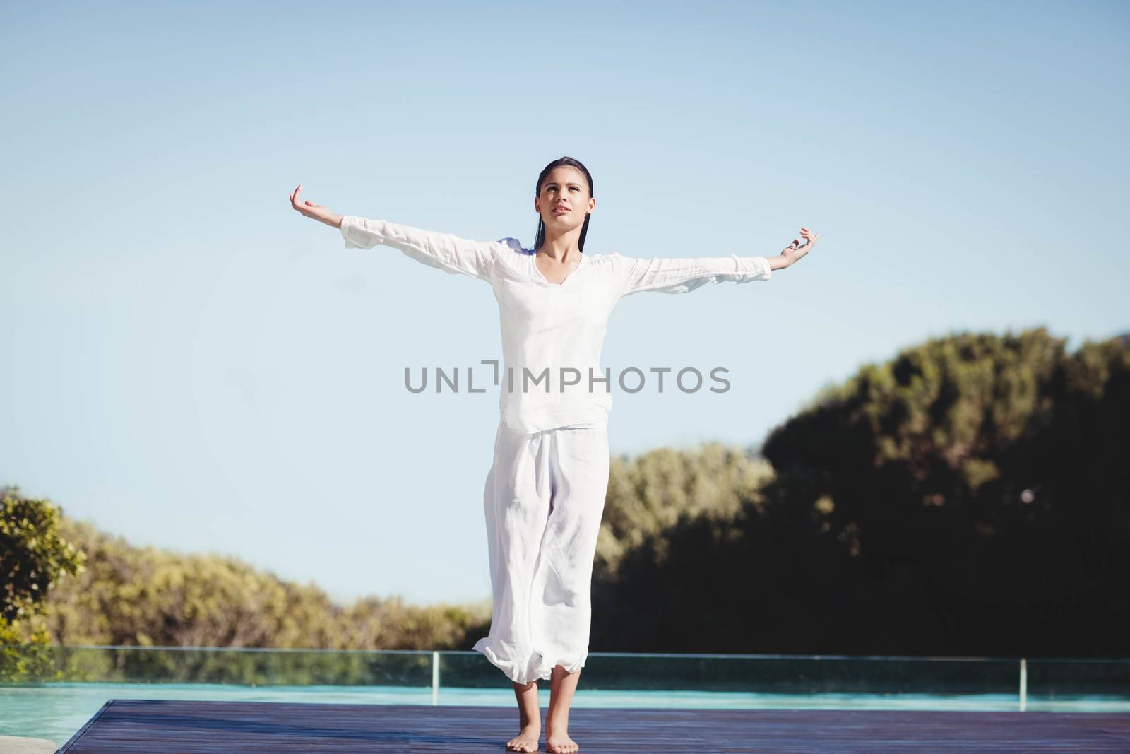 Calm brunette doing yoga by the pool