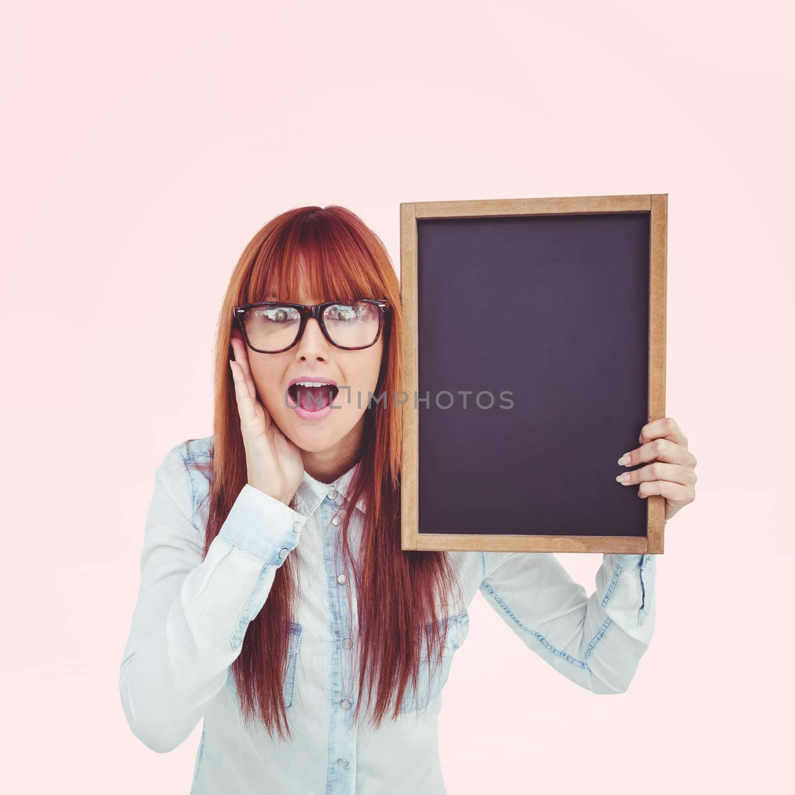 Smiling hipster woman holding blackboard against beige