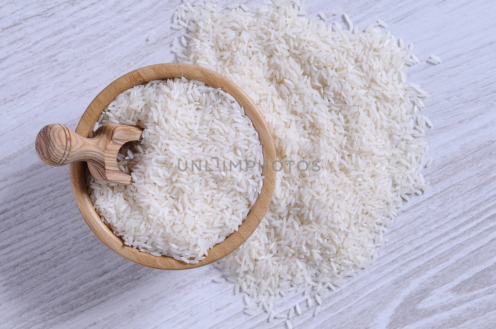 Close-up of white rice in bowl and on blue wooden table. From above