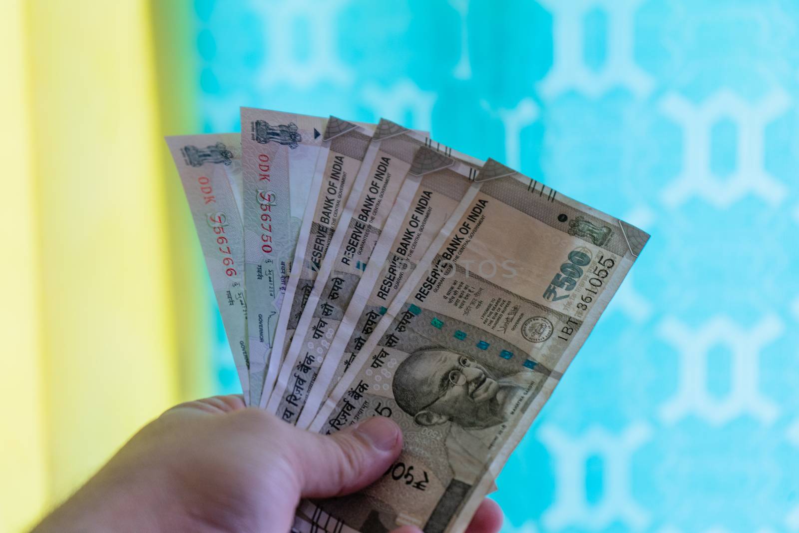 Hand holding out indian currency notes against a colorful background. Showing the currency cash problems in India