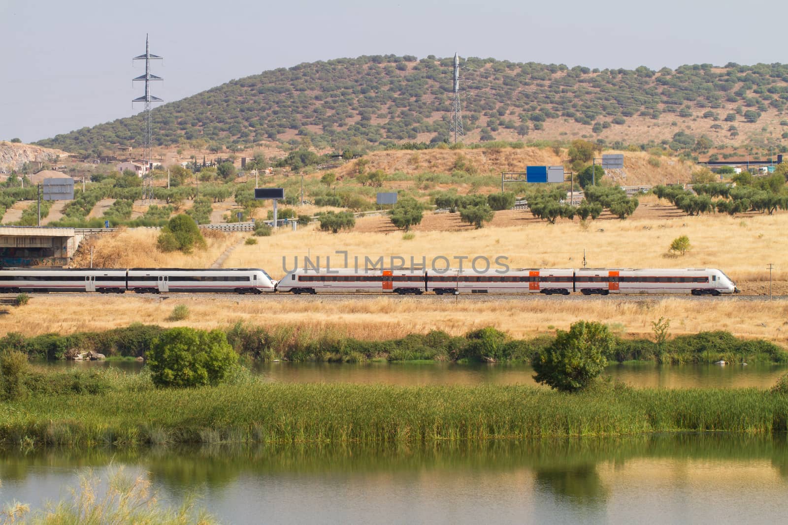 Automotive train of travelers, with diesel traction used as regional transport in Spain as it passes through Mérida with the Guadiana River in the foreground