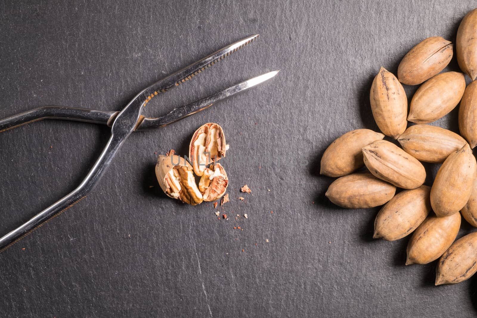 Pecan nuts with nutcracker on slate stone