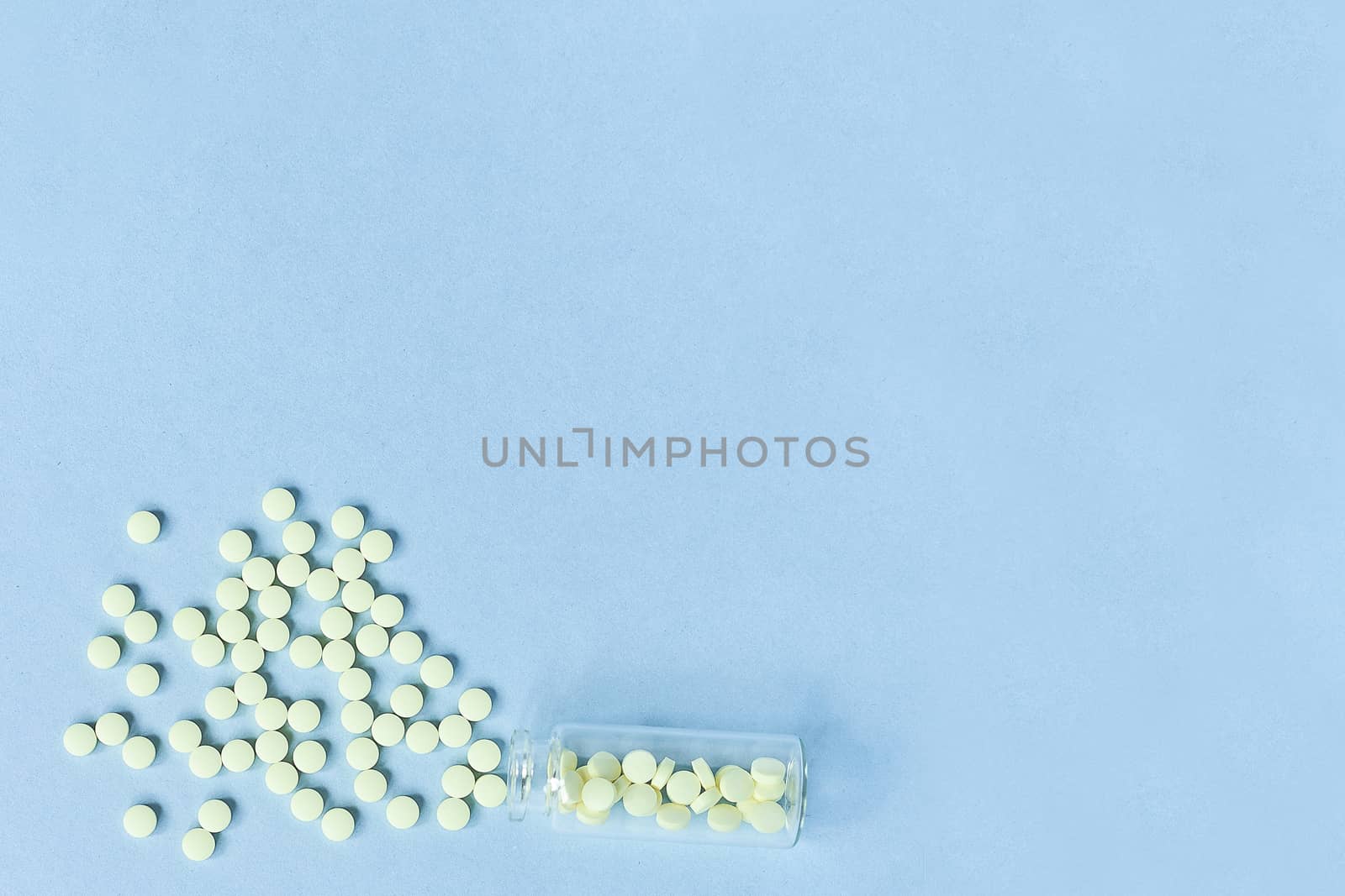 Tablets and a glass bottle on a blue background. Medicine, healthcare and tablets concept. Flatley. The view from the top. copyspace for text. yellow tablets on a pastel blue background by Pirlik