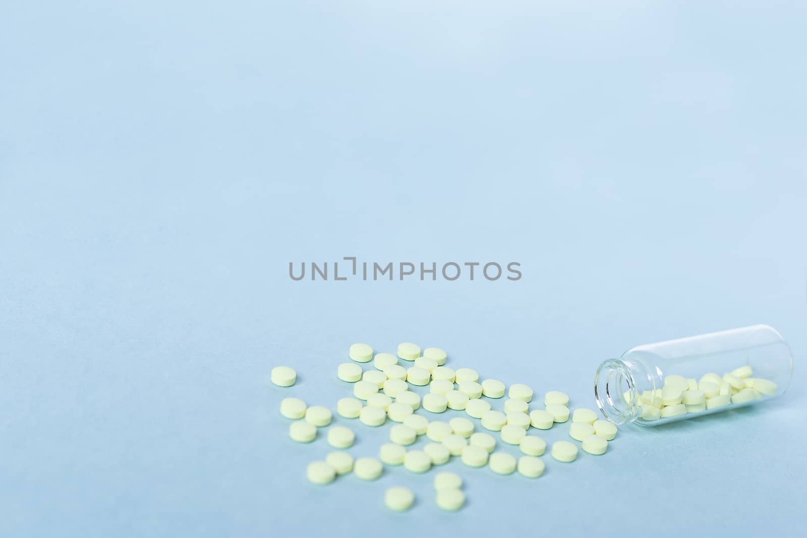 Yellow tablets and a glass bottle on a pastel blue background. Medicine, healthcare and the concept of tablets. Flatley. The view from the top. copyspace for text. blurred, blurred background by Pirlik