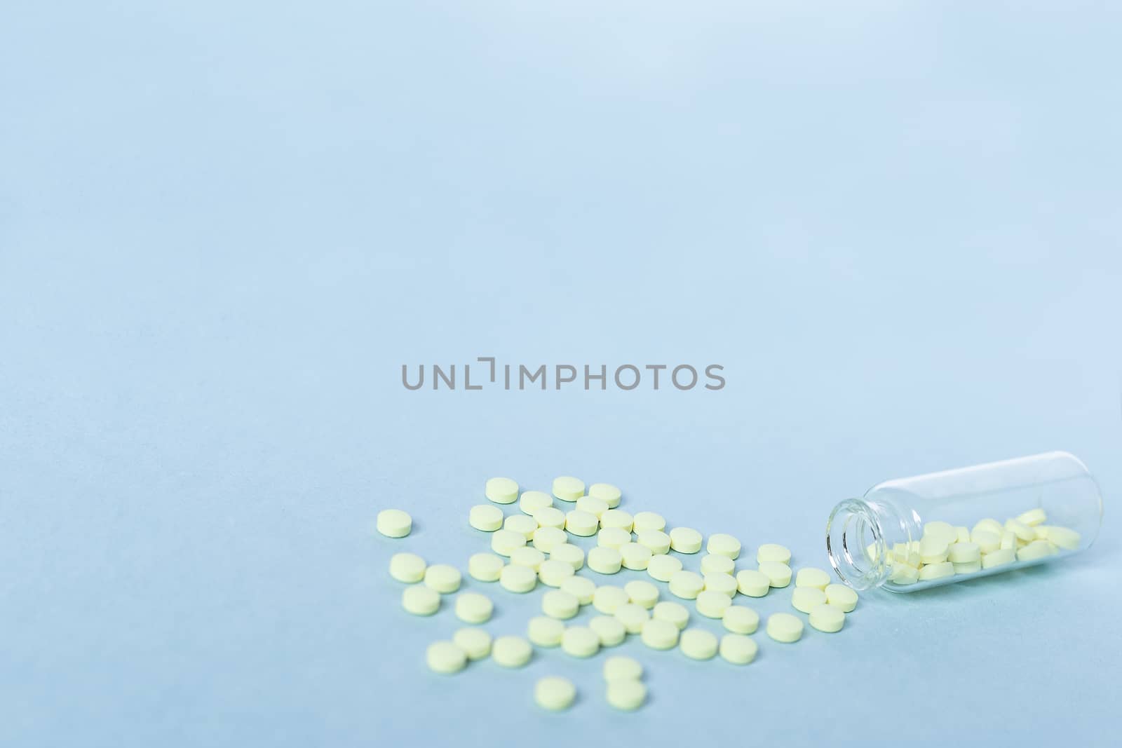 Yellow tablets and a glass bottle on a pastel blue background. Medicine, healthcare and the concept of tablets. Flatley. The view from the top. copyspace for text. blurred background, blurred