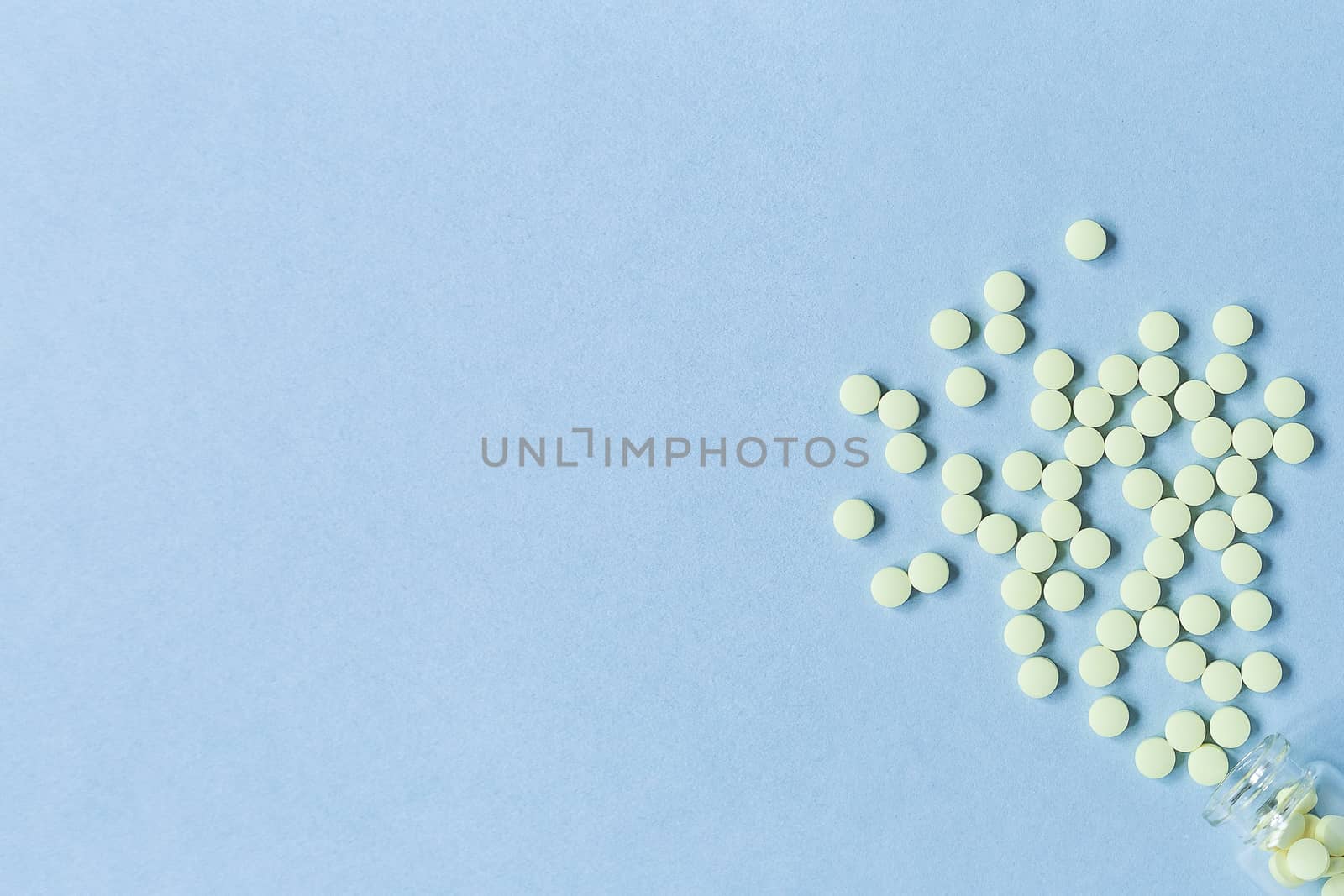 yellow tablets on a pastel blue background. Tablets and a glass bottle on a blue background. Medicine, healthcare and tablets concept. Flatley. The view from the top. copyspace for text.