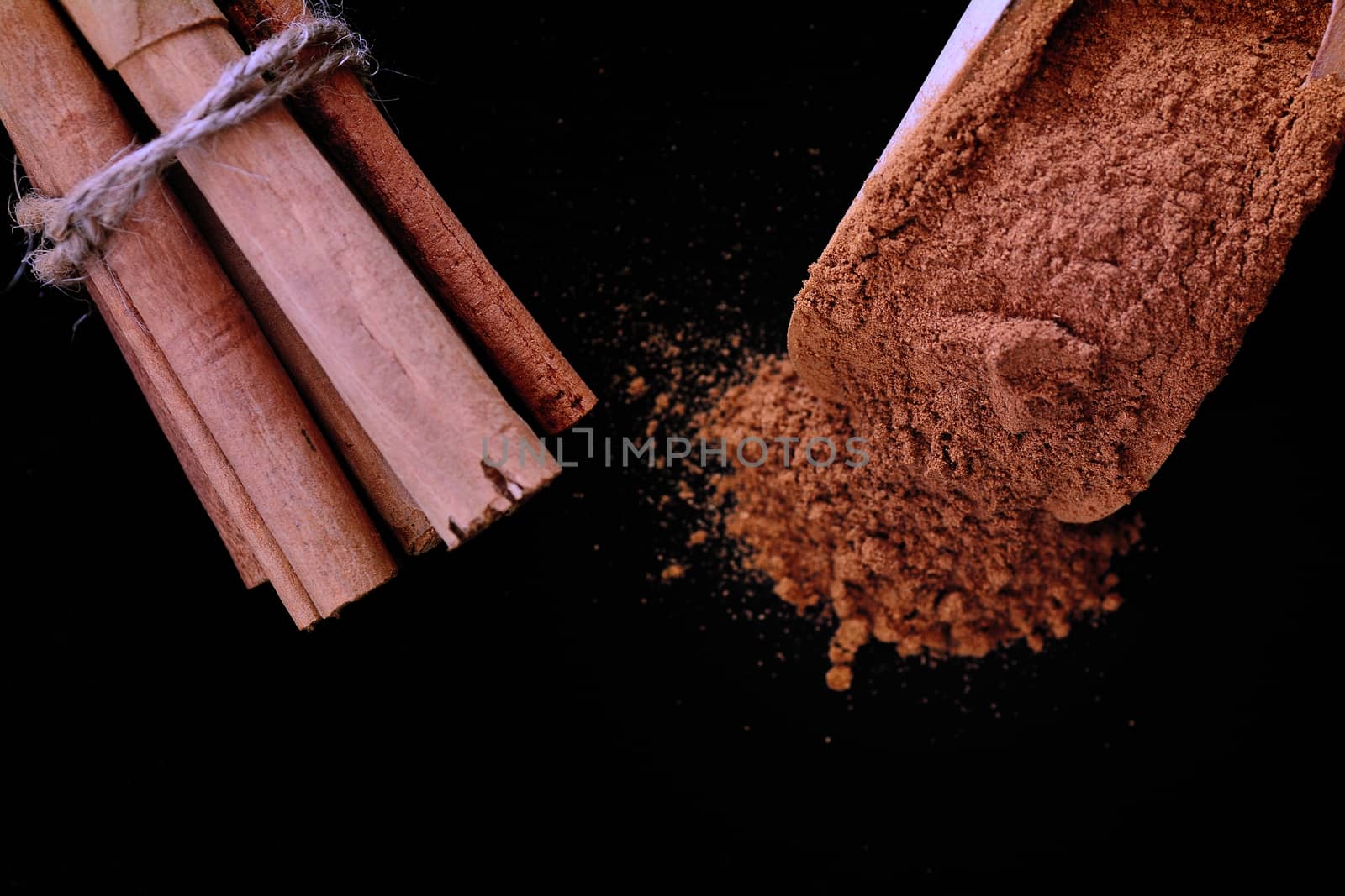 Close-up of cinnamon sticks tied with rope and powdered of black background.Copy space.