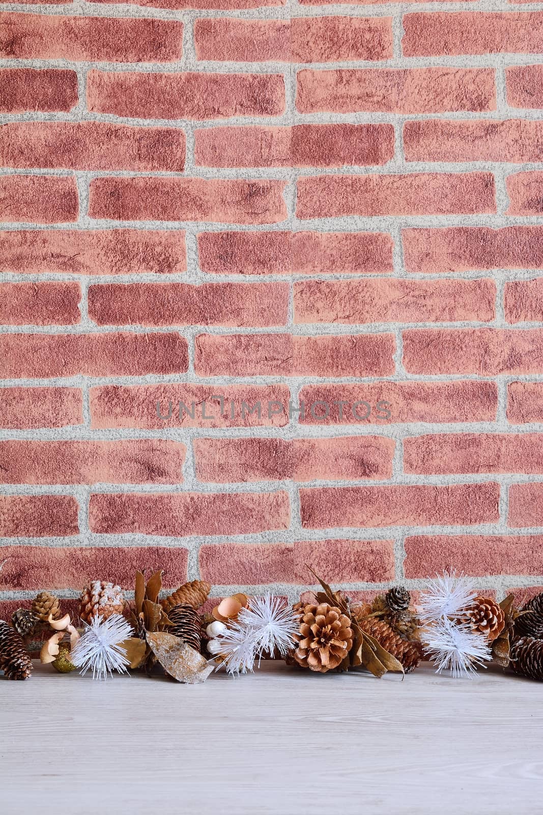 Close up of decorative Christmas garland made of pinecones lying on wooden floor against of brick wall