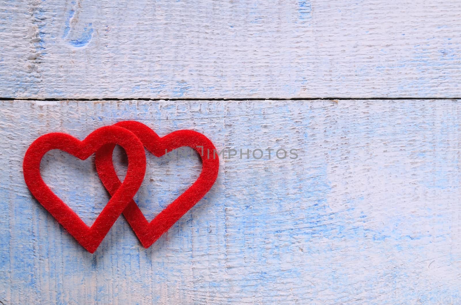 Two red hearts fabric over wooden table.