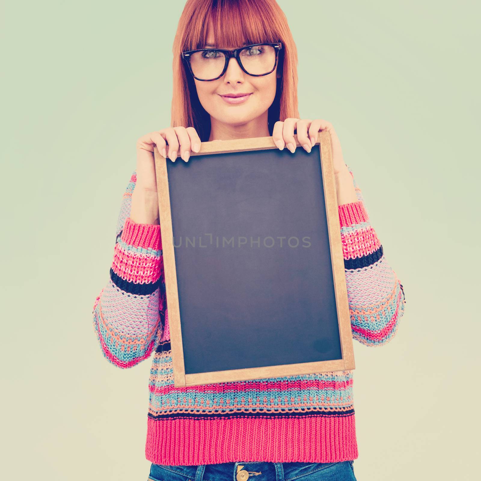 Smiling hipster woman holding blackboard against blue background